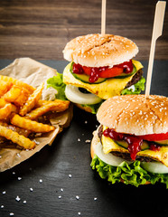 Tasty cheeseburgers with french fries served on fashionable black desk