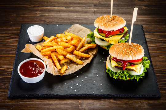 Tasty cheeseburgers with french fries served on fashionable black desk