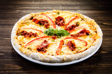 Pizza with ham and vegetables on wooden table