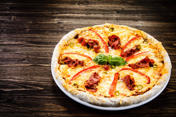 Pizza with ham and vegetables on wooden table