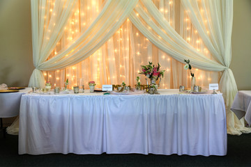 Wedding. Banquet. Chairs and honeymooners table decorated with candles, served with cutlery and...