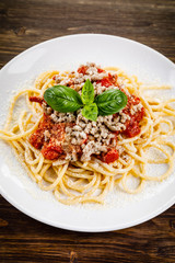 Pasta with meat and tomato sauce on wooden table
