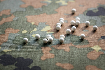 airsoft balls bbs are scattered amid camouflage fabric