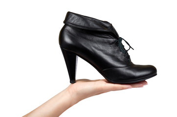Female black leather high heel shoes with hand isolated on white background