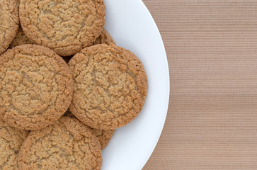 Top close view of apple pie crust cookies on a white plate atop a wood table. 