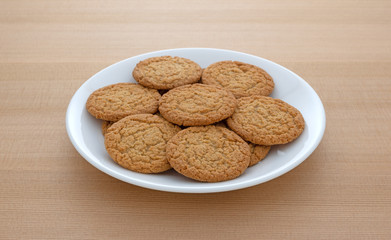 Apple pie crust cookies on a plate atop a wood table.