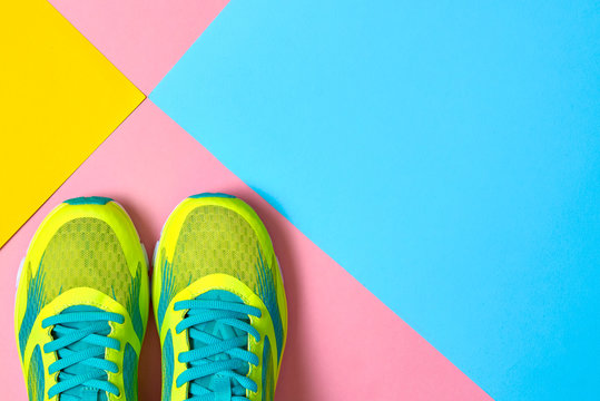 Pair of sport shoes on colorful background. New sneakers on pink, blue and yellow background, copy space. Overhead shot of running shoes. Top view, flat lay