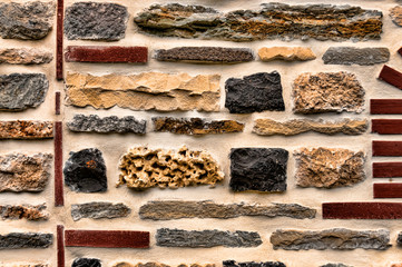 A colorful stagger of rocks and bricks cemented as a unique design for a wall.