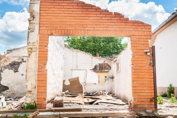 Interior remains of hurricane or earthquake disaster damage on ruined old house in the city with collapsed walls, roof and bricks with selective focus