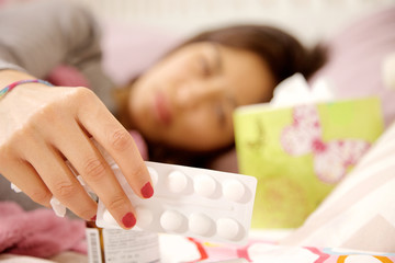 Obraz na płótnie Canvas Sick woman in bed look medicine deciding which to take