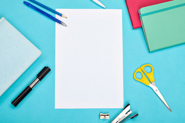 pens, scissors, notebooks and a white sheet of paper