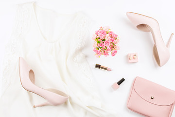Fashion blogger workspace flat lay with pumps, silk top, cosmetics, purse and flowers.
