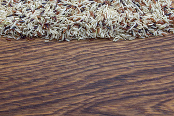 Mixed rice of three colors, red, white and black on an oak wood background