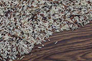Mixed rice of three colors, red, white and black on an oak wood background