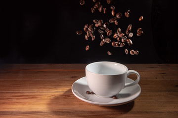 Obraz premium coffee beans falling in empthy coffee cup in black background