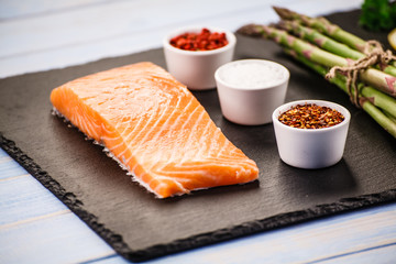 Fresh raw salmon fish served on black stone on wooden table