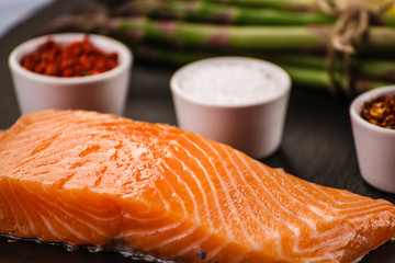 Fresh raw salmon fish served on black stone on wooden table