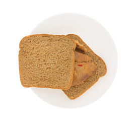Top view of a tilapia fillet in sesame sauce sandwich on a plate isolated on a white background.