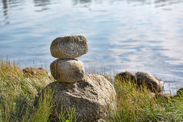 Stacked rocks in the summertime with the ocean in the background.