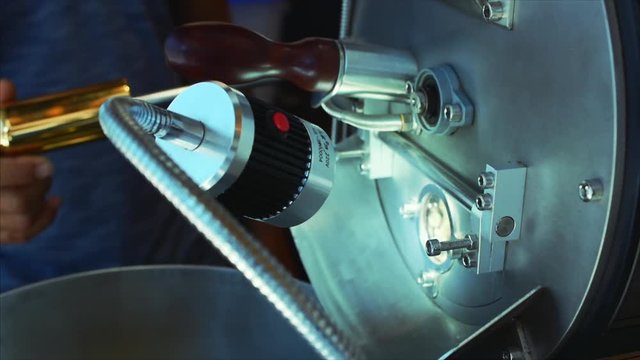 Professional coffeemachine and raw coffee beans. White coffee beans are fried in a professional machine for coffee beans to make real coffee. Slow motion.