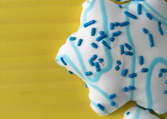 Top close view of star shaped Christmas cookies on a bright yellow table.