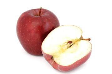 Media manzana roja, cortada por la mitad, al lado de manzana roja entera, sobre fondo blanco. 