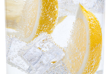 In a glass with cubes of melting ice slices of a juicy yellow lemon.