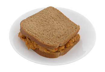 Curry flavored tuna sandwich on a plate isolated on a white background.