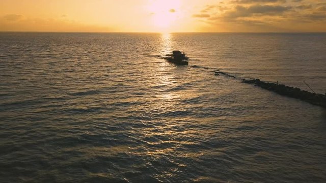 Vista aerea di sagome dei trabucchi sul mare per la pesca del pesce con pescatori alle ultime luci del tramonto.