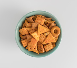 Top view of snack crackers and pretzels in a small bowl atop a white counter top.