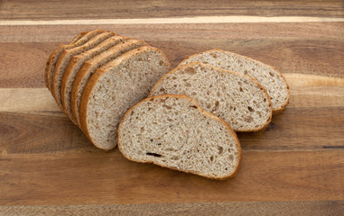 Slices in front of a small bread loaf on a wood cutting board.