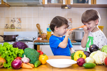 Healthy eating. Happy children prepares and eats vegetable salad in kitchen