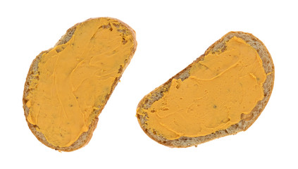 Cheese spread on two slices of wheat bread isolated on a white background.