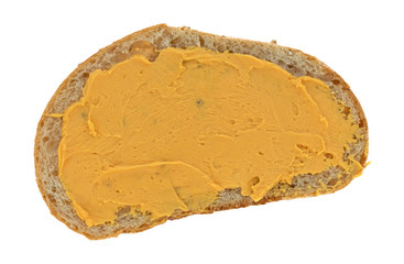 Cheese spread on a slice of wheat bread isolated on a white background.