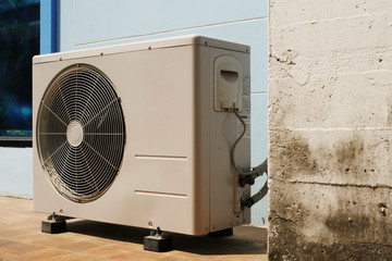 Air Conditioner Condenser Unit at a Blue Color Painted Concrete Wall