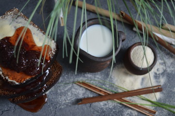 Milk in pot and bread with jam