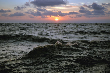 Sunset over rough water of Baltic Sea seen from a tourist boat in Leba town, Poland
