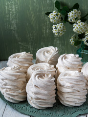 Homemade marshmallows on white wooden boards, against the backdrop of a green wall. Exquisite...