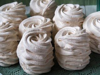 Homemade marshmallows on white wooden boards, against the backdrop of a green wall. Exquisite sweets. Apple zephyrs on a green wipes.