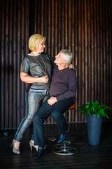 Happy married couple on brown wooden wall background. Husband and wife looking into each other's eyes