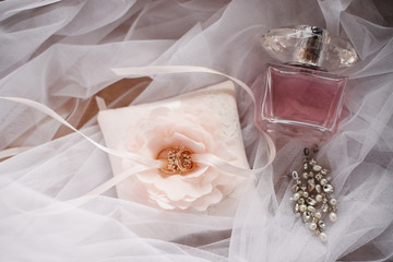 Top view of beautiful elegant wedding golden rings on pink white flower. Parfume and luxury jewelry on the table