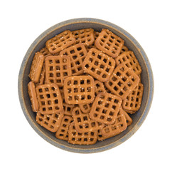 Top view of waffle pretzels in an old stoneware bowl on a white background.