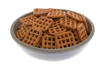 Waffle pretzels in an old stoneware bowl on a white background.