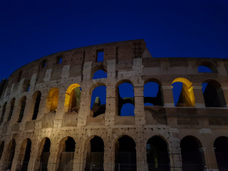 Fototapeta premium old ancient ruins of colosseum at night against dark blue sky. most famous and popular place in Rome Italy 