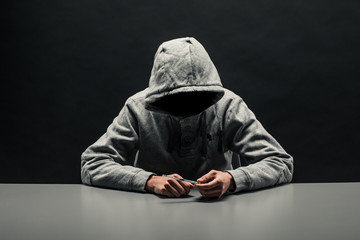 Addict in gray hoodie on the head suffers from addiction on a dark black background