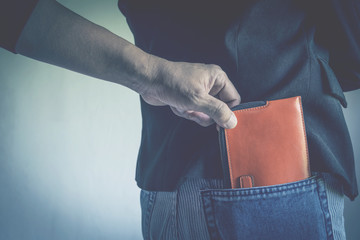 Close-up of a the hand of thief stealing the wallet to a woman. Thief stealing wallet from back...
