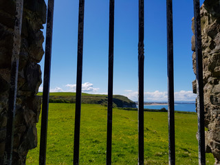 view over windows on grassy field and coast of ocean in northern ireland 