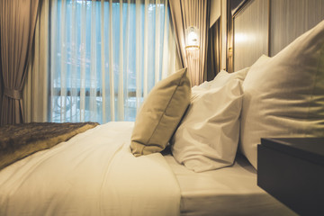 Bed maid-up with clean white pillows and bed sheets in beauty bedroom.