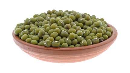 Organic mung beans in a terracotta bowl isolated on a white background.
