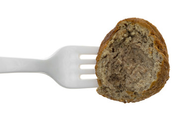Top view of a bitten meatball on a plastic fork.